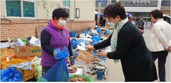 ▲강진읍시장에서 물건을 구입 후 강진사랑상품권으로 결재를 하고 있다.(사진제공=강진군)