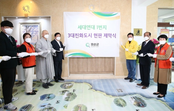 ▲지난해 3월 열린 3대 친화도시 현판 제막식에 참석한 구충곤 화순군수가 주민 대표와 함께 기념촬영하는 모습(사진제공=화순군)