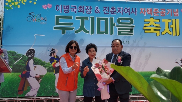 ▲이병국 회장‧진춘자여사 자택준공을 기념해 마련된 순천시 왕조1동 두지마을 축제가 성황리에 열린 가운데 박진숙 완조1동 통장협의회장이 이병국회장 ‧진춘자여사에게 꽃다발을 전달하고 있다(사진 이기장 기자)